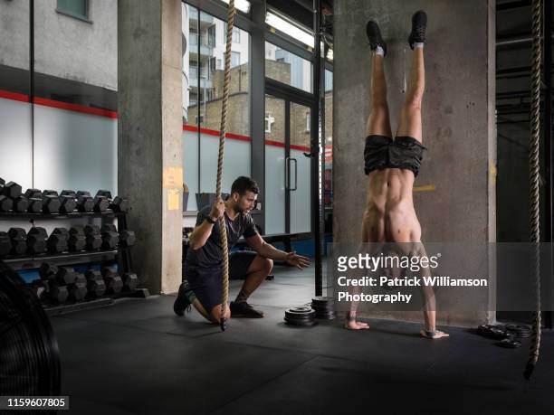 man motivating friend doing handstand in gym - fare la verticale sulle mani foto e immagini stock