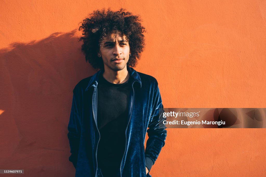 Portrait of young man against orange coloured wall