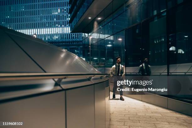 businessman walking past mirrored wall of office building, milano, lombardia, italy - walking past office wall stock pictures, royalty-free photos & images