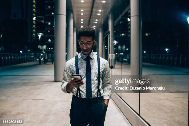 businessman using smartphone, walking past mirrored wall of office building, milano, lombardia, italy - walking past office wall stock pictures, royalty-free photos & images