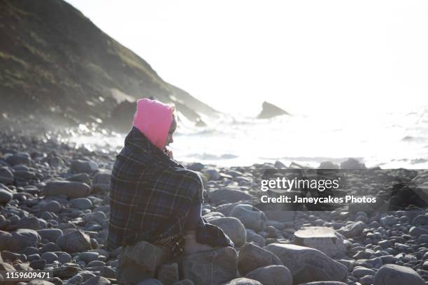 girl in deep thought on rocks by sea - survival blanket stock pictures, royalty-free photos & images