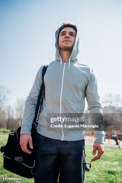calisthenics at outdoor gym, young man carrying sports bag - carrying sports bag foto e immagini stock