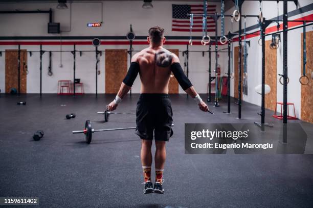 tattooed young man training, skipping in gym, rear view - skip ストックフォトと画像