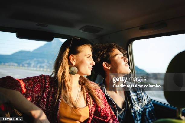 young couple traveling by car, sunset light - car sharing stock pictures, royalty-free photos & images