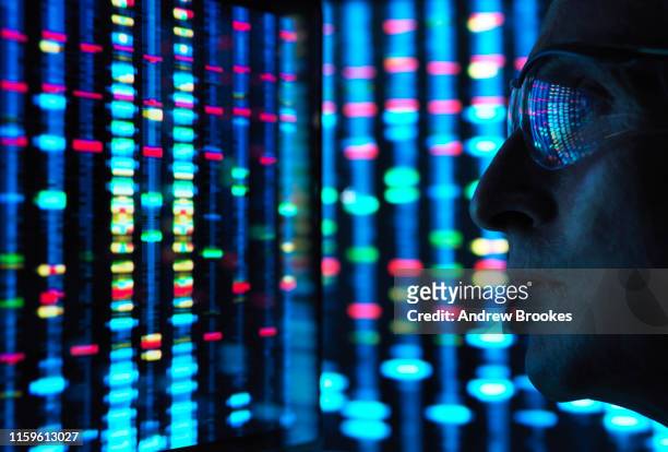 genetic research, scientist viewing dna information on screens - light discovery stock-fotos und bilder