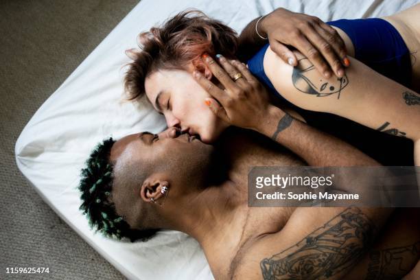 a young lgbt couple kissing and hugging in bed - a young couple stock pictures, royalty-free photos & images