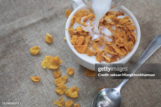 close-up of milk being poured in corn flakes on table - corn flakes imagens e fotografias de stock