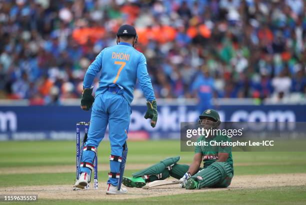 Sabbir Rahman of Bangladesh plays a shot and falls over as MS Dhoni of India looks on during the Group Stage match of the ICC Cricket World Cup 2019...