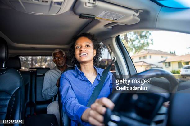 joven mujer negra conduciendo coche para rideshare - conductor oficio fotografías e imágenes de stock