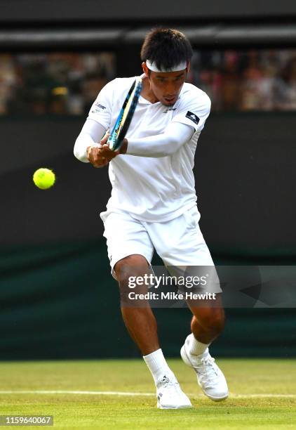 Yuichi Sugita of Japan plays a backhand in his Men's Singles first round match against Rafael Nadal of Spain during Day two of The Championships -...