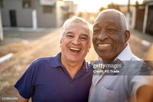 glückliche senior-freunde, die ein selfie auf der straße machen - 2 guys black white stock-fotos und bilder