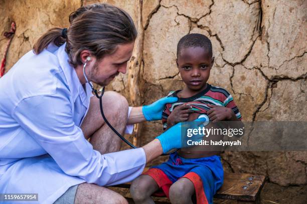 doutor que examina o menino africano novo na vila pequena, kenya - missionário - fotografias e filmes do acervo