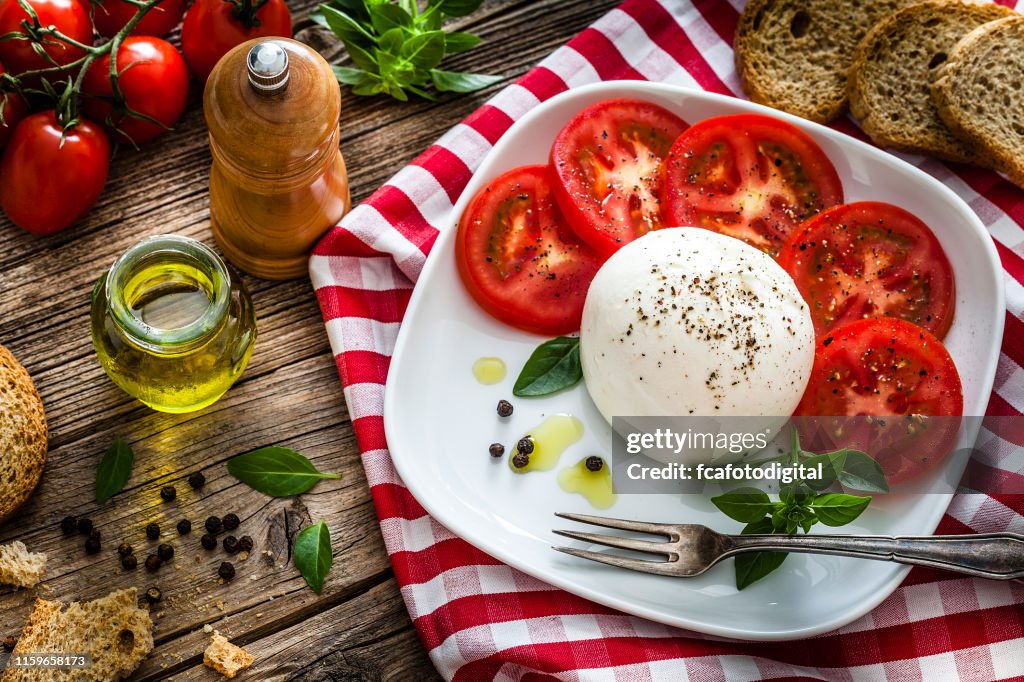 Healthy fresh burrata cheese salad on rustic wooden table