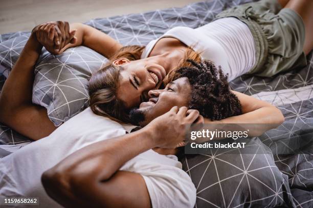 junges paar liegenbett im schlafzimmer und lächelnd - man and woman kissing in bed stock-fotos und bilder