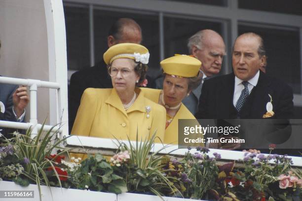Queen Elizbeth II, Princess Anne and Henry Herbert, 7th Earl of Carnarvon , racing manager to Queen Elizabeth II, watching the horseracing at the...