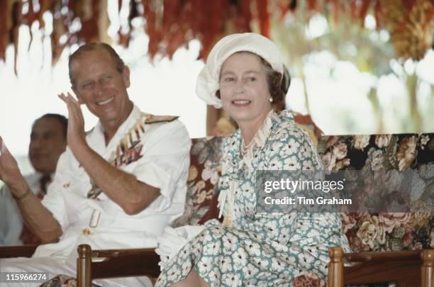 Prince Philip and Queen Elizabeth ll, wearing hat designed by miliner Frederick Fox, smiling as they are entertained in Tuvalu, as part of their tour...