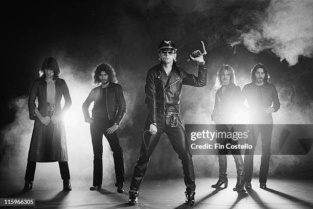 Judas Priest , British heavy metal band, pose against a dark background, with smoke and light, in a group studio portrait, circa 1978.