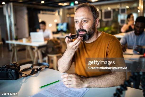 man sending voice message on smart phone from the office - voice command stock pictures, royalty-free photos & images