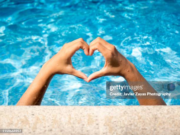 woman forming heart-shape with hands - swimming pool and hand stock-fotos und bilder