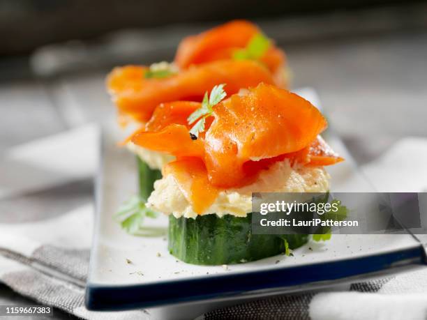 gurkenkanape mit geräuchertem lachs und geröstetem knoblauch hummus - räucherlachs stock-fotos und bilder