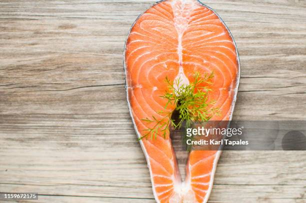 raw salmon steak garnished with dill on a wooden table - pube stock-fotos und bilder