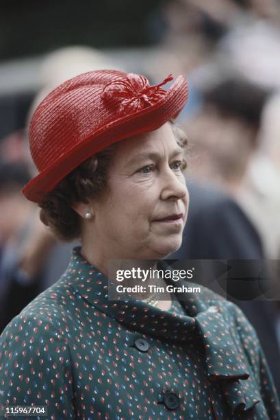 Queen Elizabeth II wearing a red hat designed by miliner Frederick Fox, attending the Sandringham Flower Show on the Sandringham estate, Norfolk,...