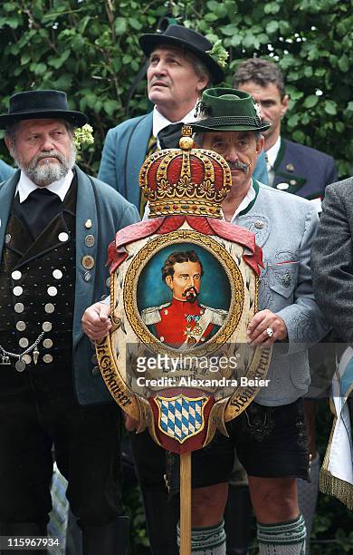 Man wearing a traditional Bavarian costume holds asign showing King Ludwig II during a religious mass to be held in honour of the 125th anniversary...