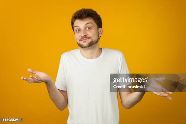 studio portrait of a 27 year old man with a beard in a white t-shirt on a yellow background - hand palm stock pictures, royalty-free photos & images