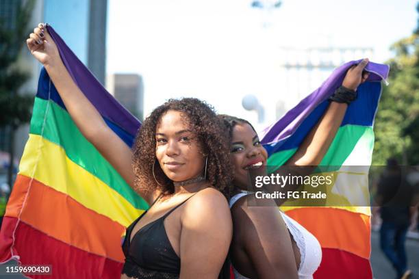 portret van vrienden wuivende rainbow flag tijdens pride parade - gay flag stockfoto's en -beelden