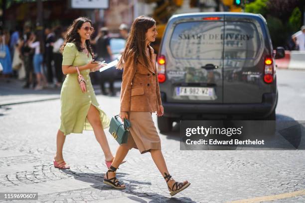 Guest wears a Christian Dior tan-color suede jacket, a green Christian Dior bag, light camel bermuda shorts, black gladiator espadrilles, outside...