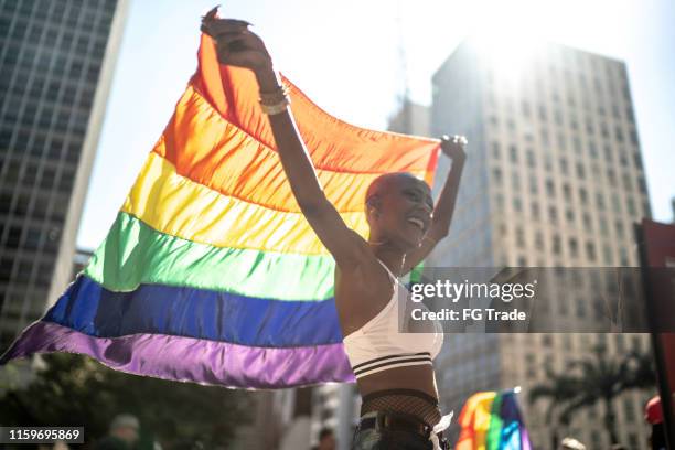 confident lesbian woman holding rainbow flag during pride parade - parada militar imagens e fotografias de stock