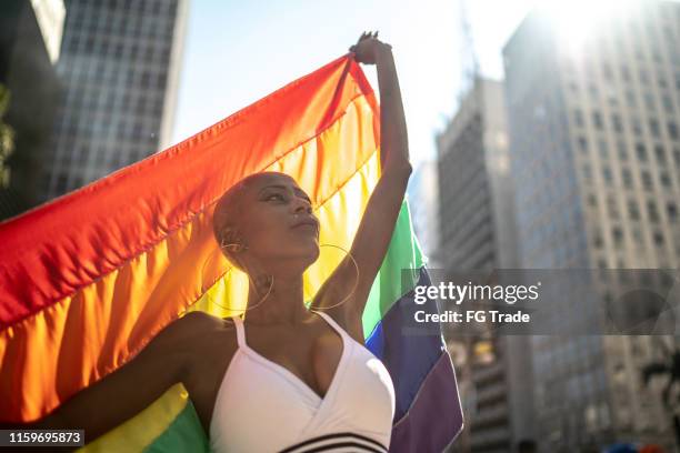 confident lesbian woman holding rainbow flag during pride parade - daily life in sao paulo stock pictures, royalty-free photos & images