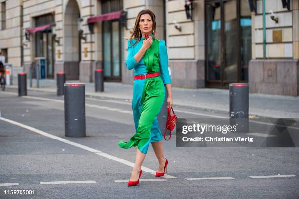 Füsun Lindner is seen wearing blue green two tone dress Escada with red belt, red round bag, red heels during Mercedes Benz Fashion Week Berlin on...