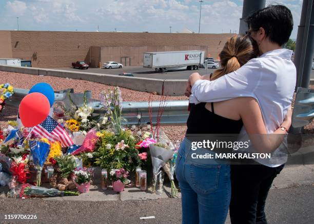 People hug beside a makeshift memorial outside the Cielo Vista Mall Wal-Mart where a shooting left 20 people dead in El Paso, Texas, on August 4,...