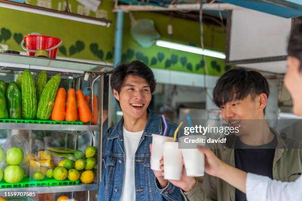 young asian men making a celebratory toast with juice - juice bar stock pictures, royalty-free photos & images