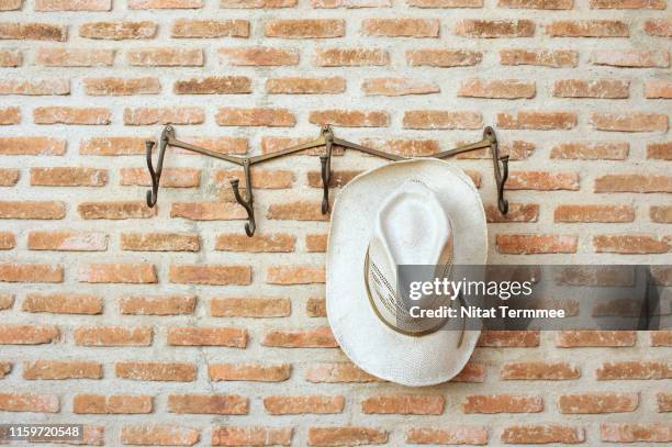 hat hanging on the brick wall. - white hat fashion item stock pictures, royalty-free photos & images