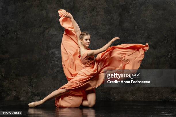 ballerina. a young ballet dancer dressed in a long peach dress, pointe shoes with ribbons. the girl performs an elegant, graceful dance movement. beautiful classic ballet. advertising ballet school. - ballet dancers russia stockfoto's en -beelden