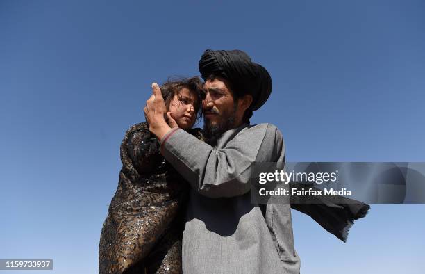 Abdul Haq carries his 4-year-old-daughter, Khadija, through the Regreshan IDP camp in Herat Province, Afghanistan, June 17, 2019. Abdul sustained...