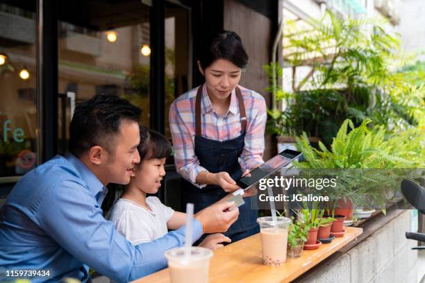 vater und tochter mit kontaktlosem bezahlen in einem café - asian family cafe stock-fotos und bilder