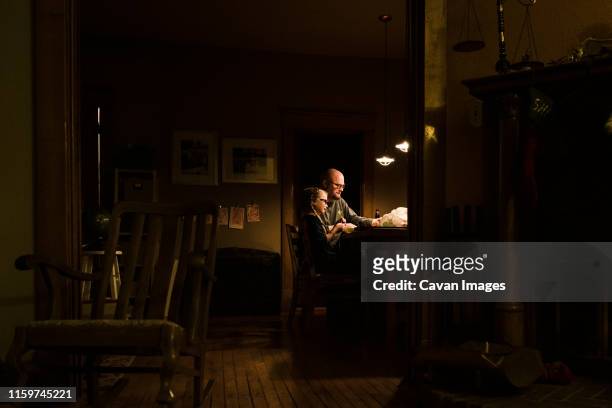 dad and daughter sit at dining room table - family night stock pictures, royalty-free photos & images