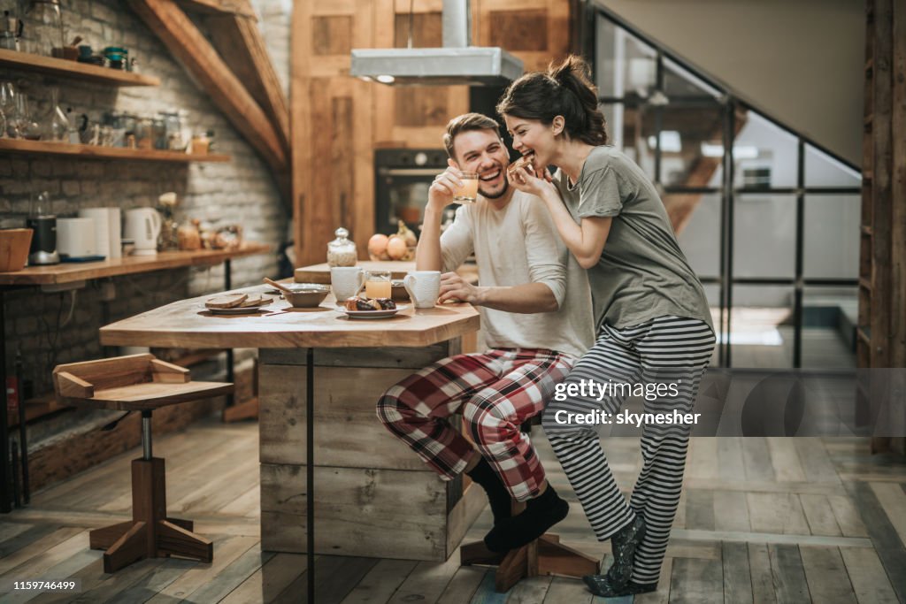 Pares felizes que têm o divertimento durante o tempo do pequeno almoço em casa.