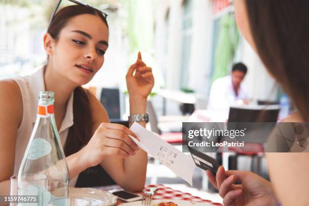femmes payantes au restaurant, partageant le chèque - se diviser photos et images de collection
