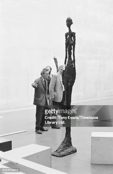 Swiss sculptor and painter Alberto Giacometti at the Tate Gallery with one of his sculptures, London, July 1965. With him are David Sylvester and...