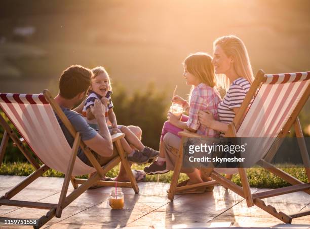 gelukkige familie die plezier in ligstoelen bij zonsondergang. - backyard deck stockfoto's en -beelden
