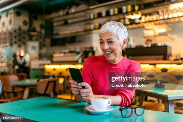 she's found the cafe with the fastest wifi - senior women cafe stock pictures, royalty-free photos & images