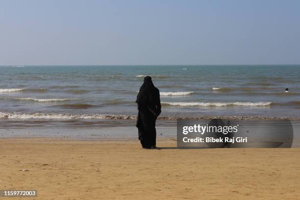 a muslim woman in burka near the sea - muslim woman beach stock pictures, royalty-free photos & images