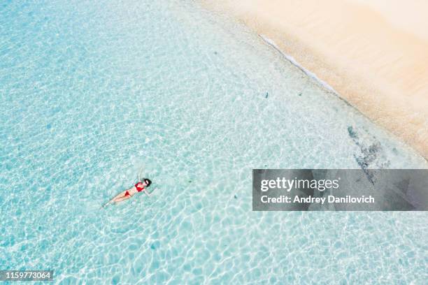 bali, mujer flotando en mar turquesa transparente. disparo aéreo de drones. - see through swimsuit fotografías e imágenes de stock