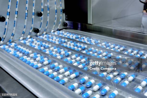 capsule package at production line - farmaceutische-fabriek stockfoto's en -beelden