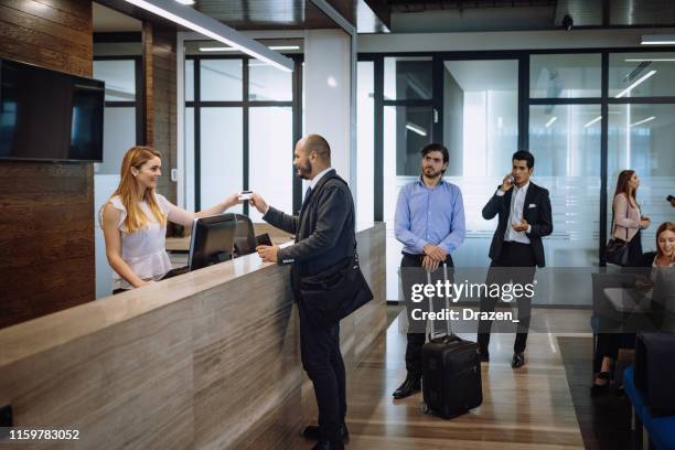 viaggiatori d'affari che controllano in hotel di lusso - lobby foto e immagini stock