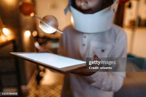 boy in the role of an astronaut with digital tablet - saturn planet stock pictures, royalty-free photos & images